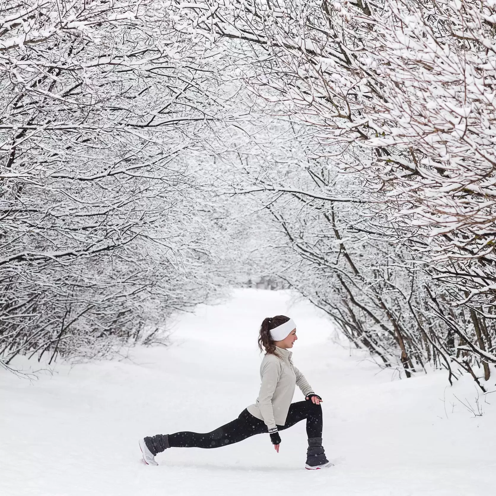 Woman stretching on a cold snowy day.
