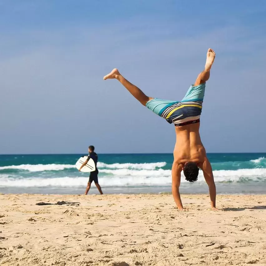 A man doing a cartwheel on the beach.
